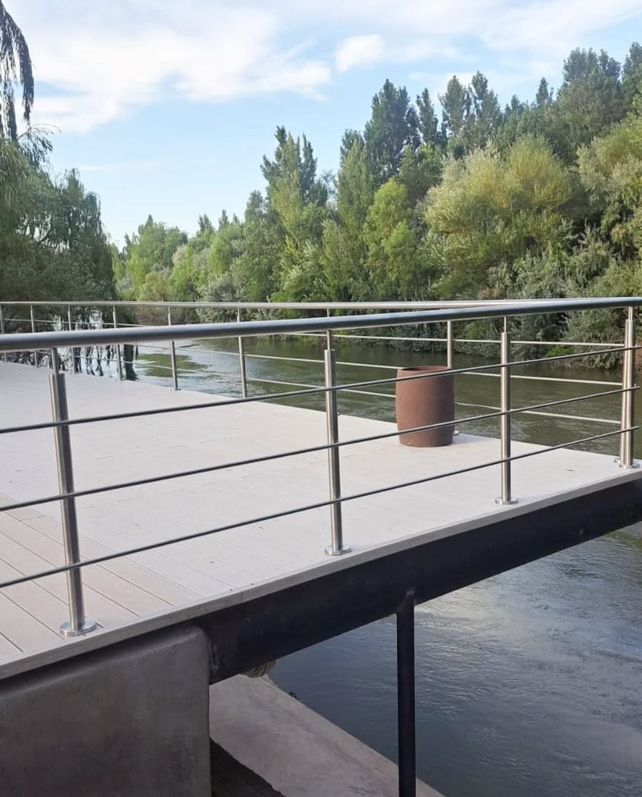 Baranda de acero inoxidable en pasarela exterior junto a un río