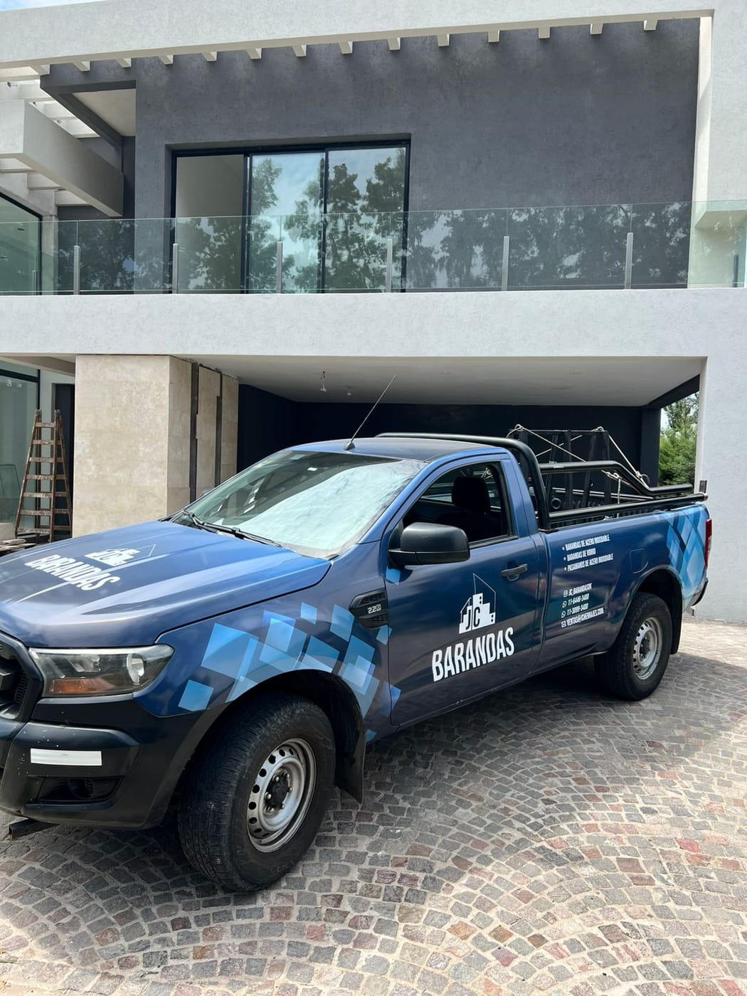 Camioneta de JC Barandas frente a una vivienda con balcones de barandas de acero inoxidable