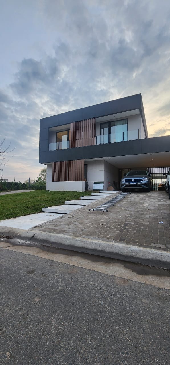 Fachada de vivienda moderna con baranda de vidrio y acero inoxidable en balcón