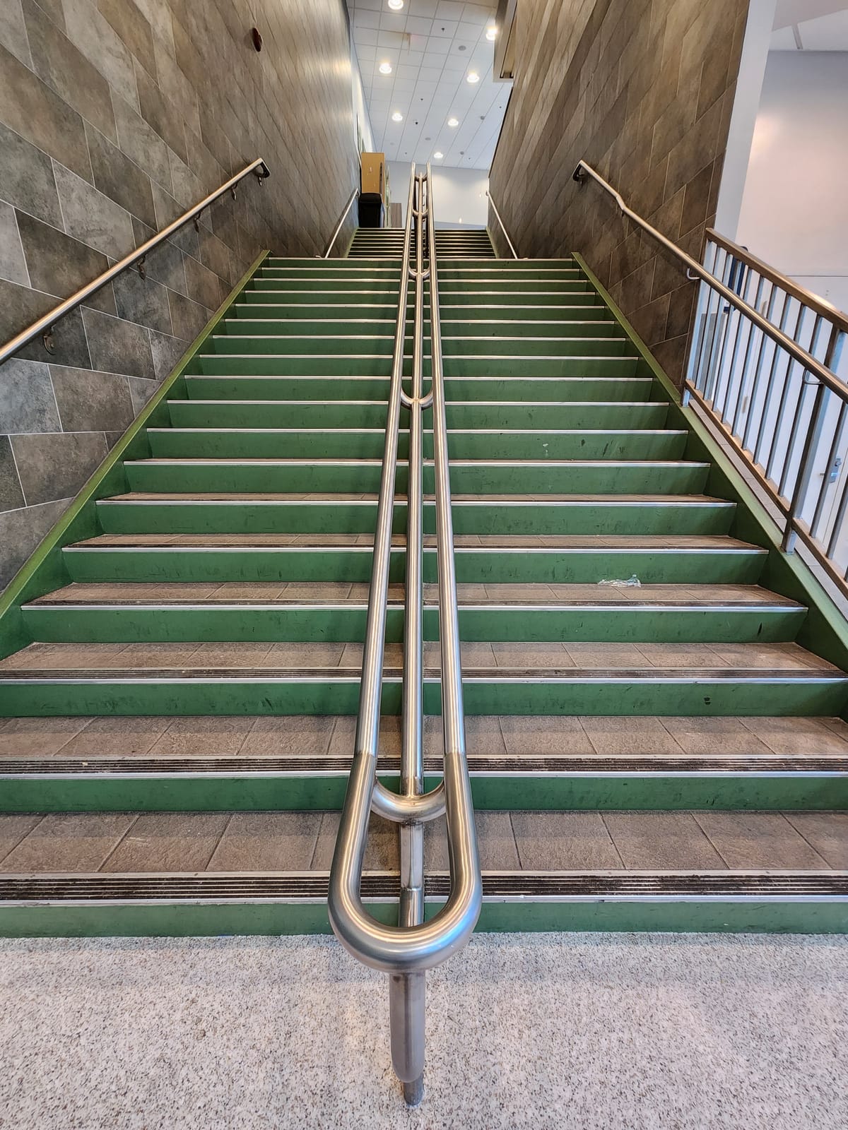 Detalle de pasamanos curvo de acero inoxidable en escalera