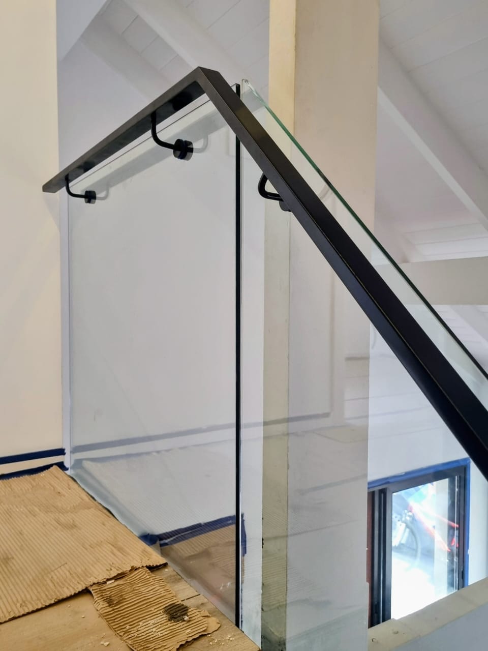 Detalle de sujeción de vidrio con herraje de acero inoxidable en baranda a medida