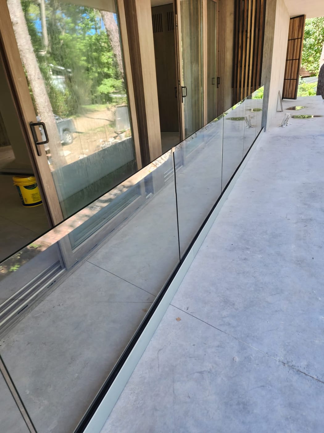 Detalle de baranda de vidrio templado junto a carpintería de madera