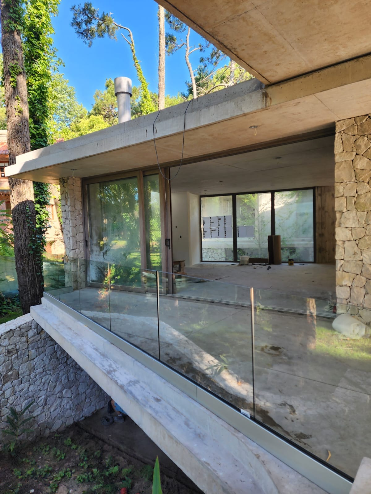 Vivienda en Cariló con baranda de vidrio templado y estructura de piedra y hormigón