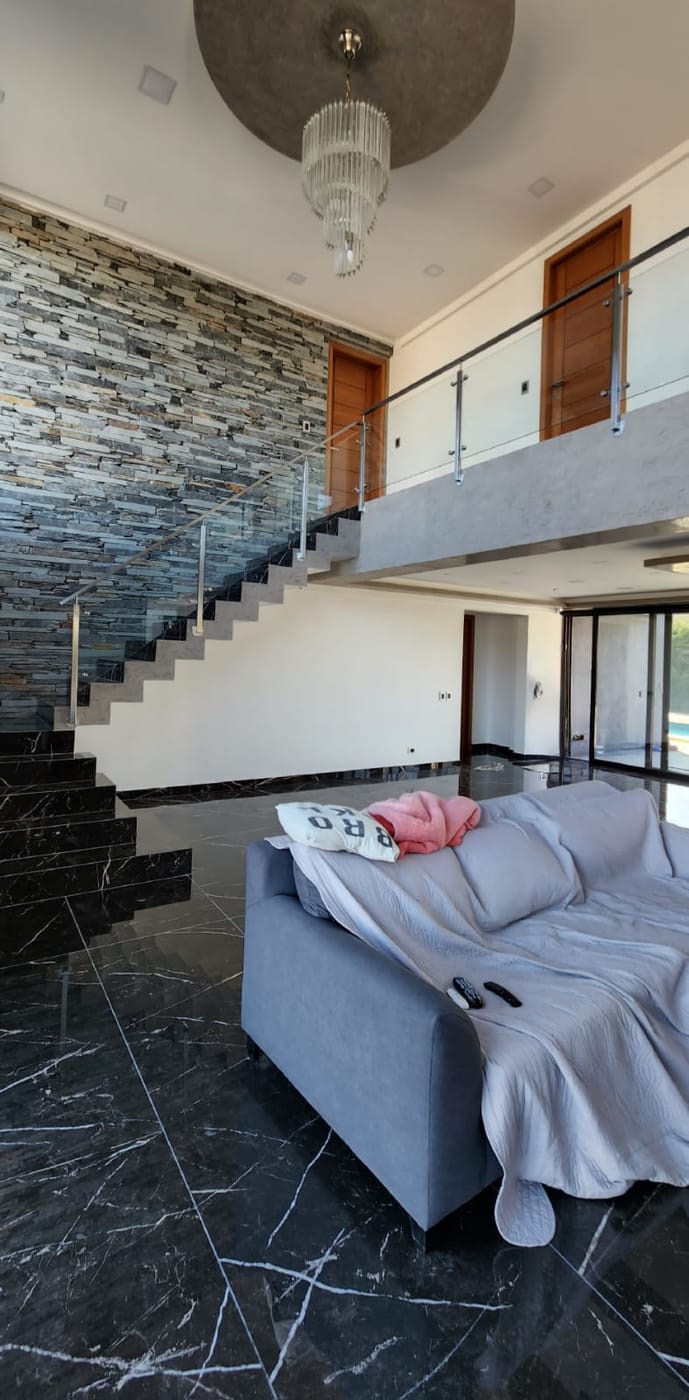 Escalera con baranda de acero inoxidable y vidrio en vivienda de Haras Santa María