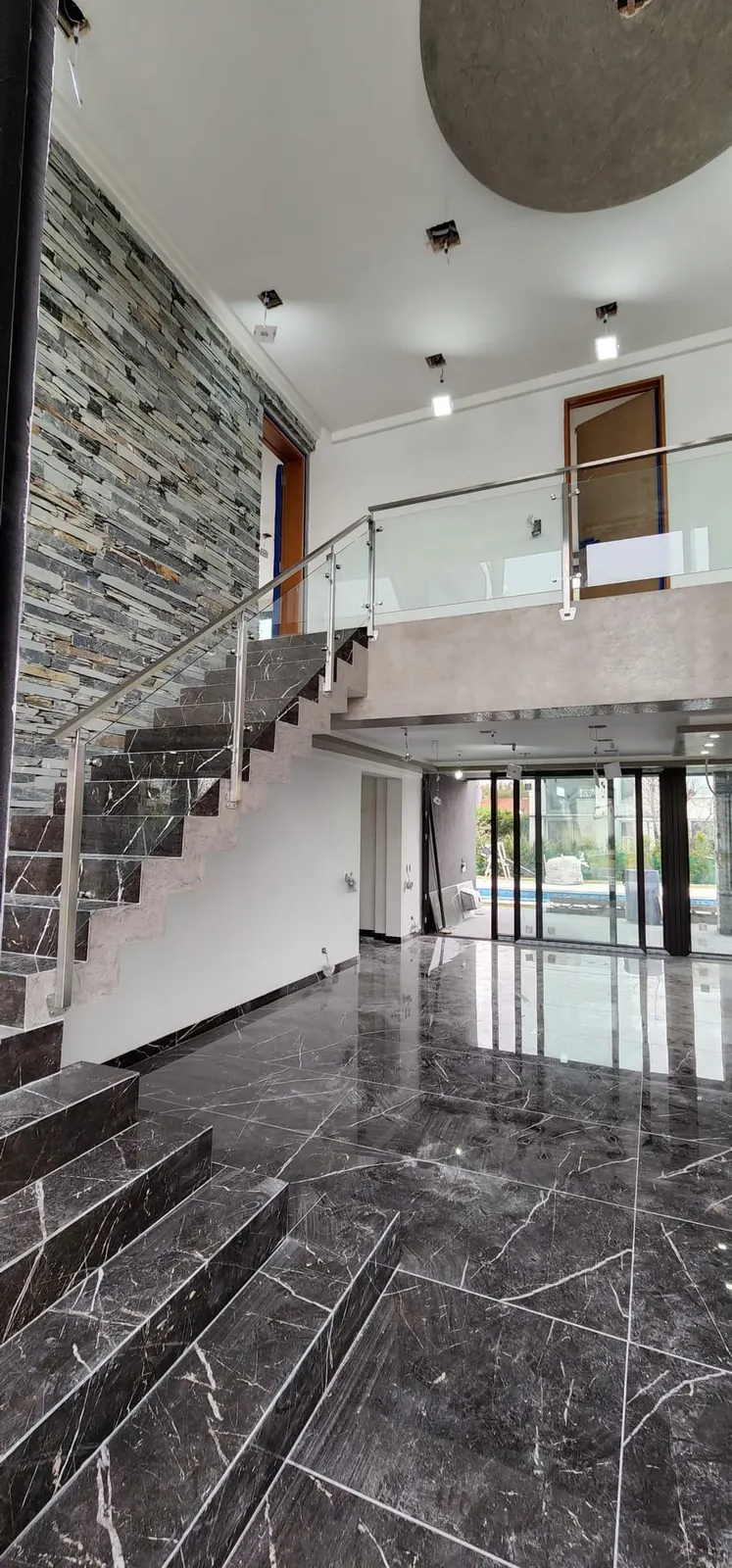 Baranda de acero inoxidable con paneles de vidrio en el entrepiso de una vivienda en Haras Santa María