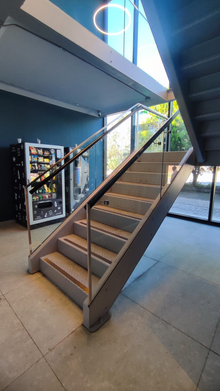 Escalera con baranda de acero inoxidable y vidrio en edificio Tenaris