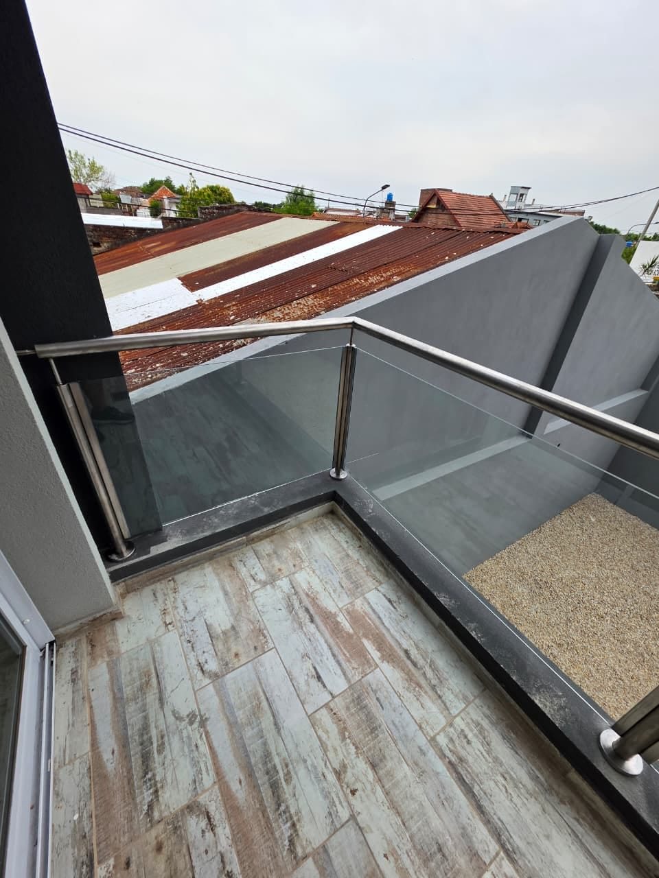 Baranda de vidrio y acero inoxidable en balcón de edificio en Tigre