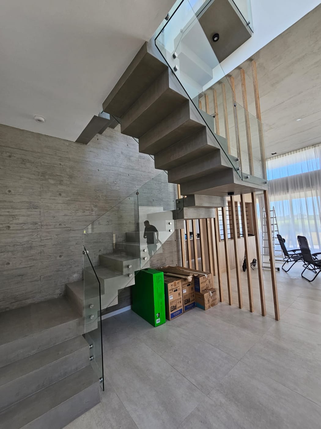 Baranda de vidrio templado y botones en escalera de hormigón, obra en etapa de mudanza