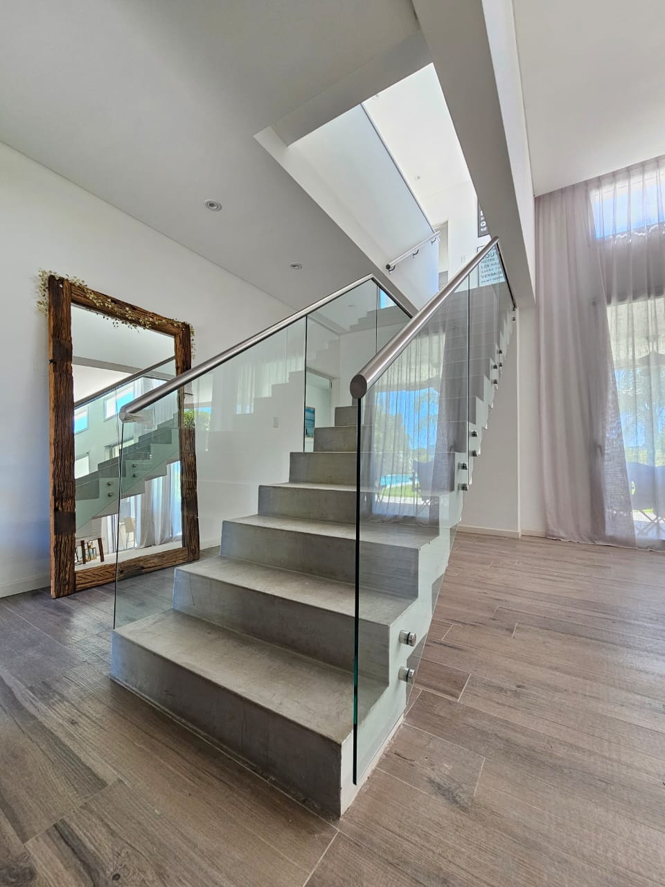 Escalera de hormigón con baranda de vidrio templado, pasamanos y botones de acero inoxidable