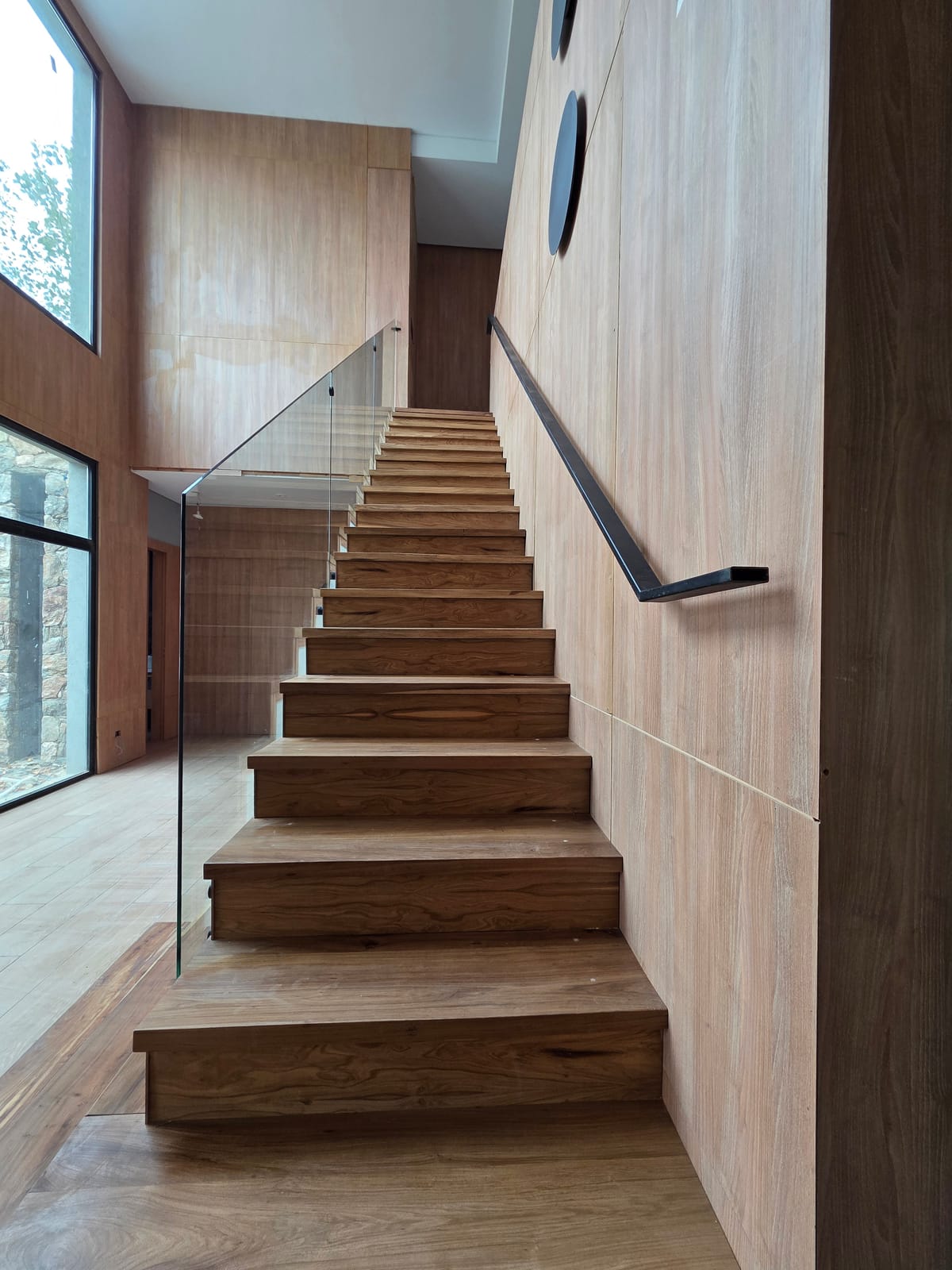 Escalera de madera con estructura de acero inoxidable y baranda de vidrio templado