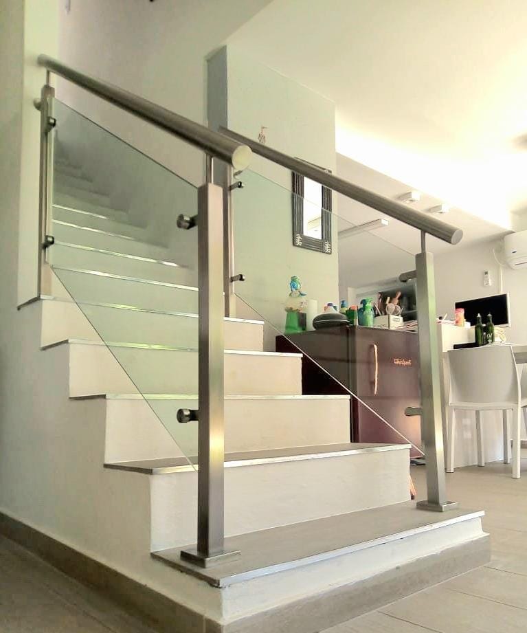 Detalle de baranda de vidrio templado con estructura de acero inoxidable en escalera interior