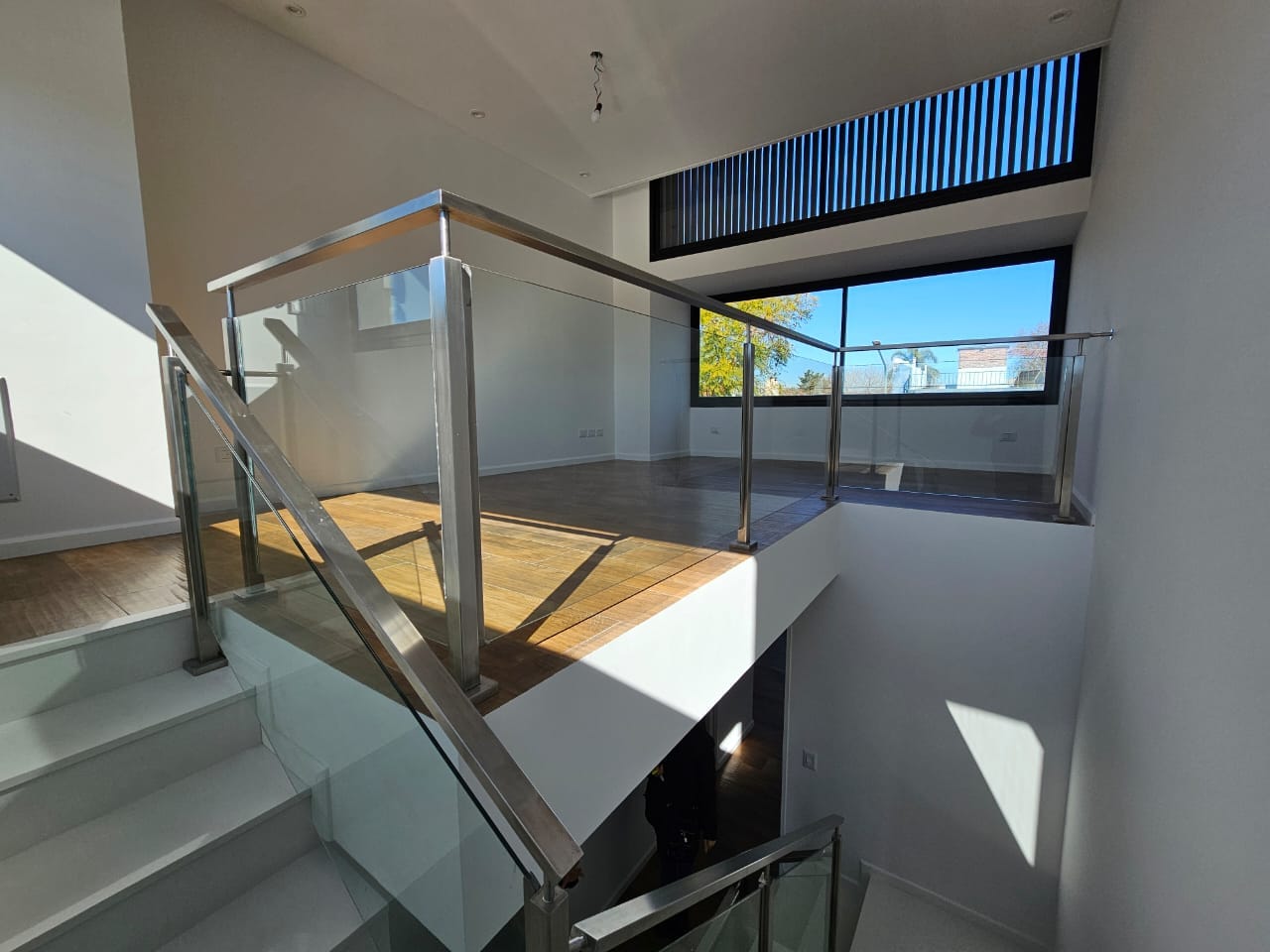 Baranda de vidrio templado con estructura de acero inoxidable en balcón interior luminoso