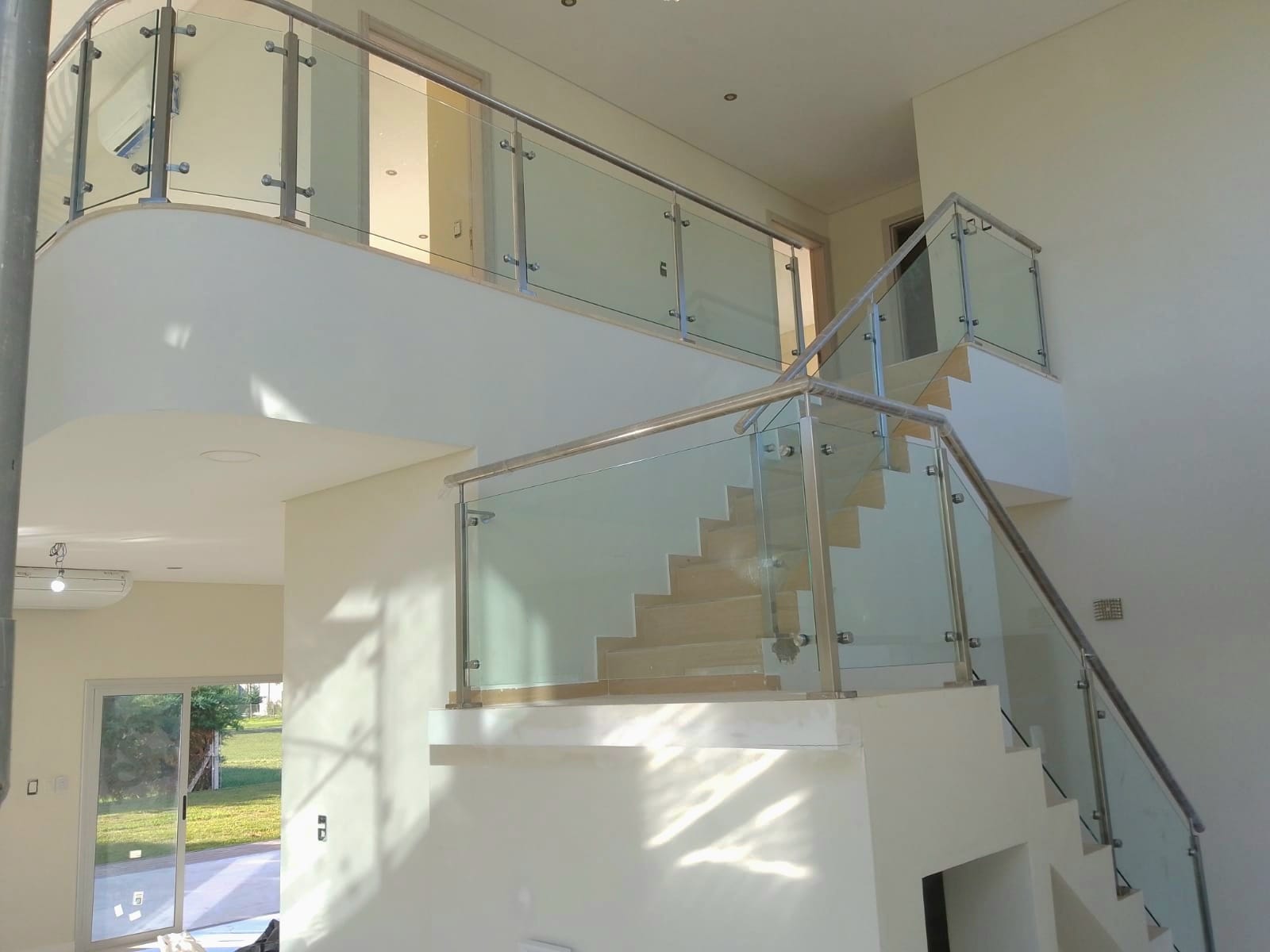 Escalera de doble altura con baranda de vidrio templado y estructura completa de acero inoxidable