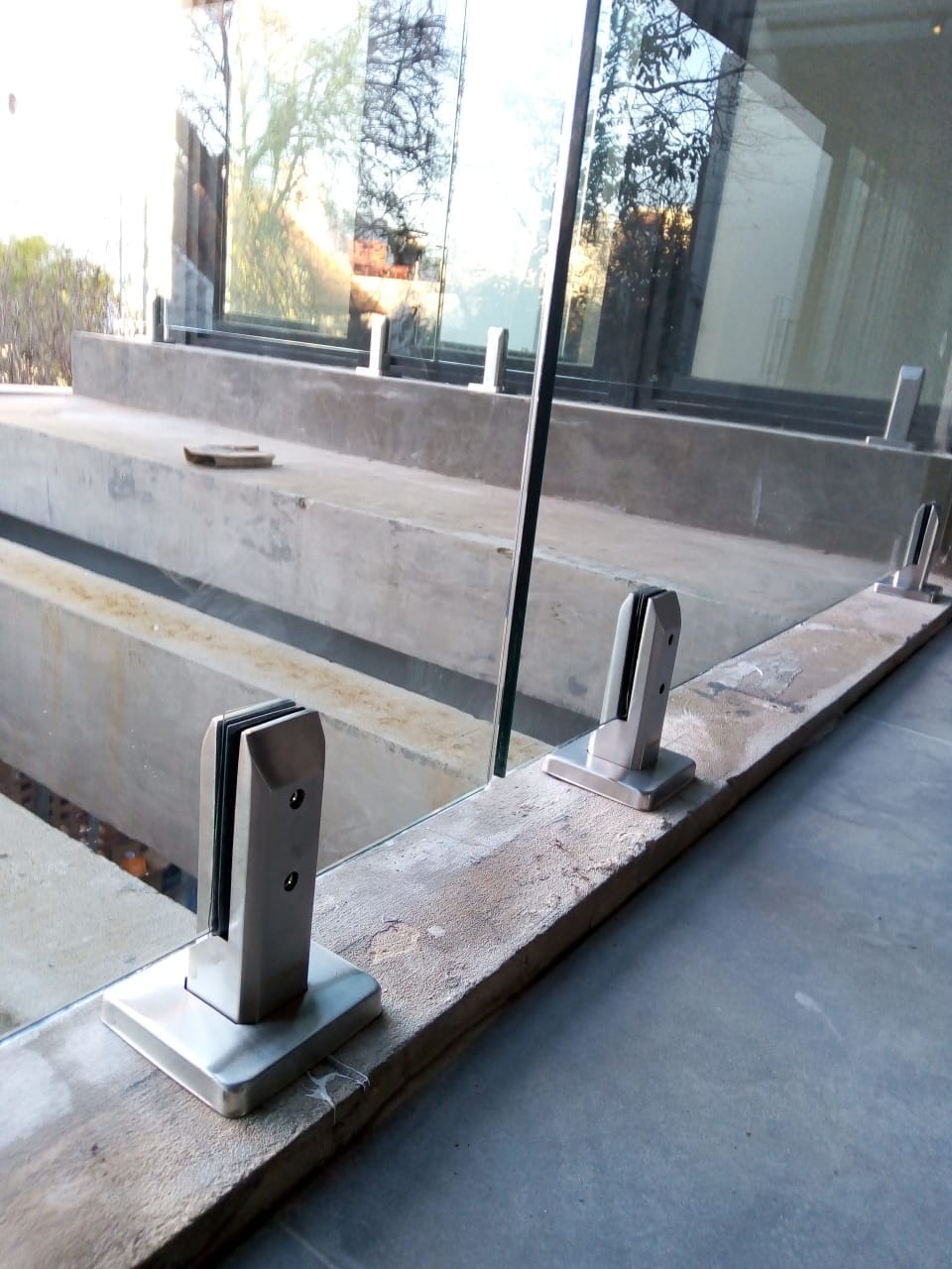 Detalle de minipostes de acero inoxidable sujetando baranda de vidrio en terraza